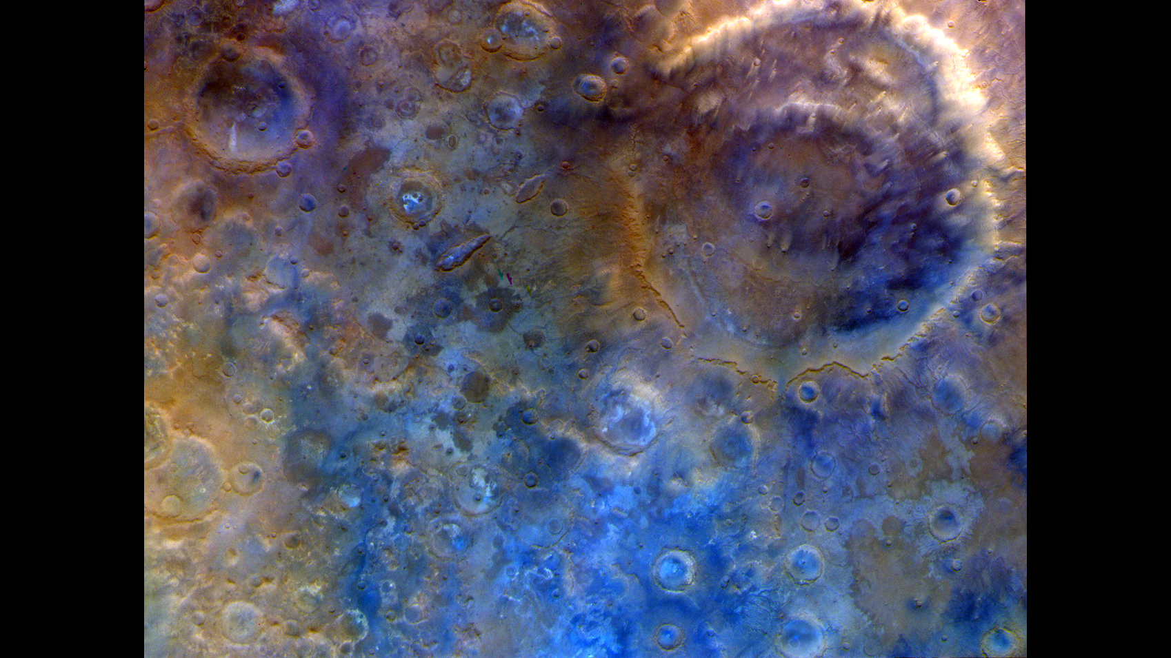 A false-color, top-down view of a Martian surface densely pockmarked with impact craters of various sizes, highlighted in vivid shades of blue, tan, and purple to differentiate geological materials.